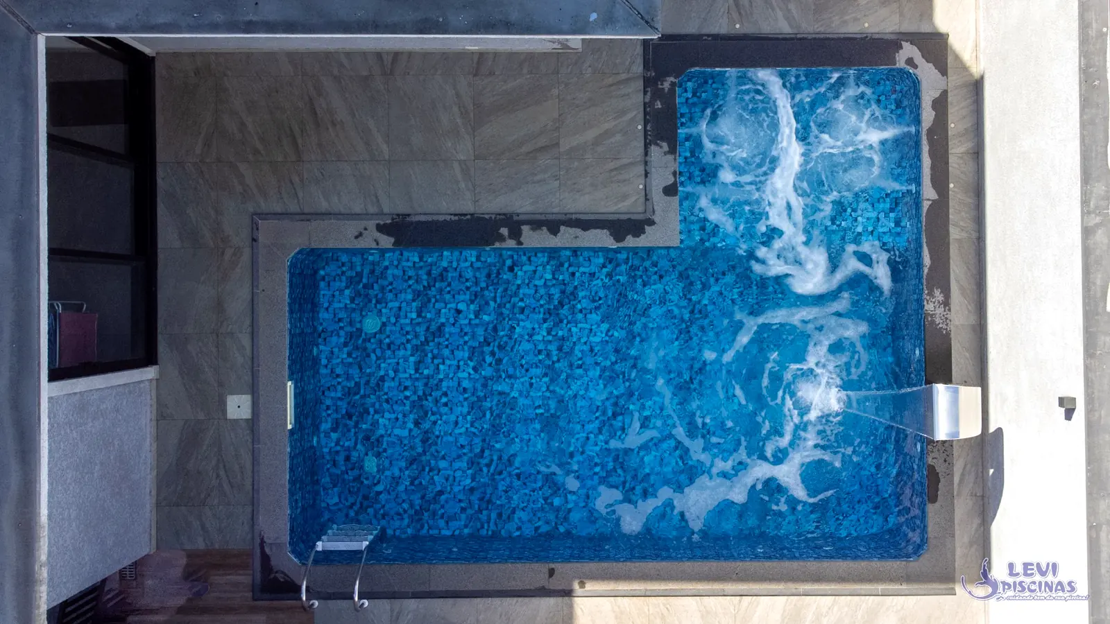 Piscina residencial com hidromassagem e cascata de inox vista por drone