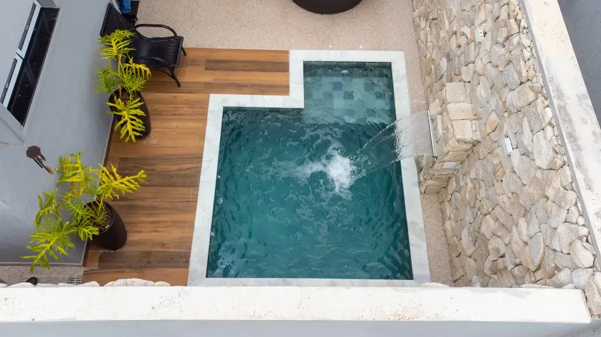 Piscina compacta com cascata e revestimento de pedra